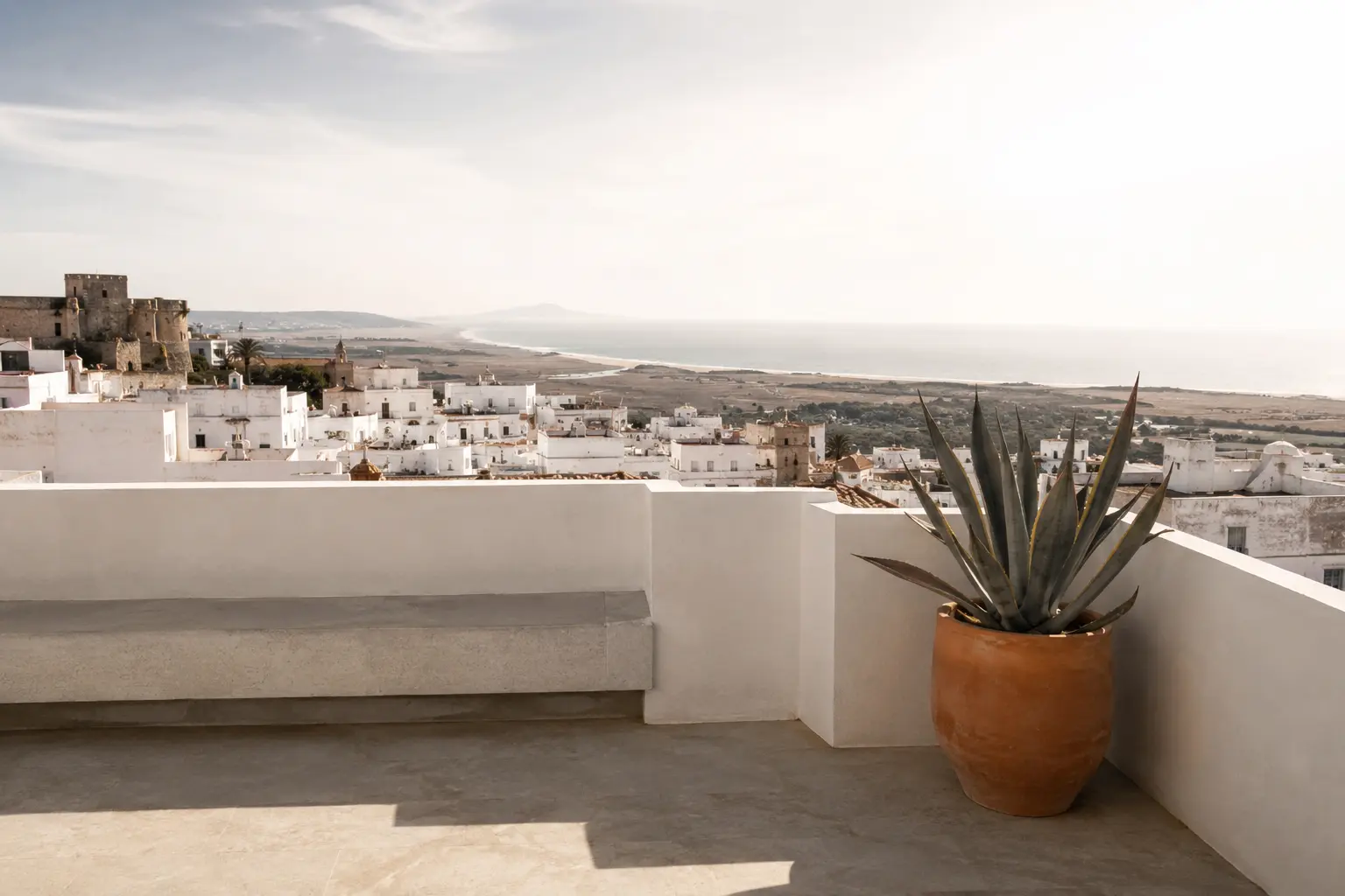 Casa entre cales — azotea sobre los tejados del pueblo blanco de Vejer, con agave y el mar al fondo